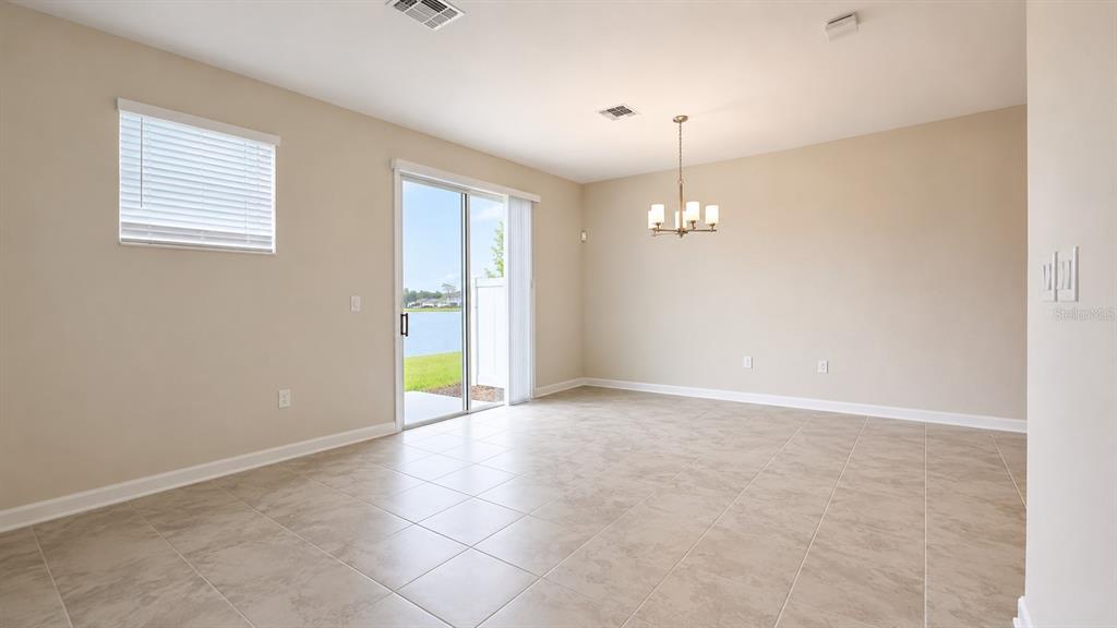 An empty dining room with tile floors, a chandelier, and a sliding glass door — 4836 TRIBUTE TRAIL, KISSIMMEE, FL