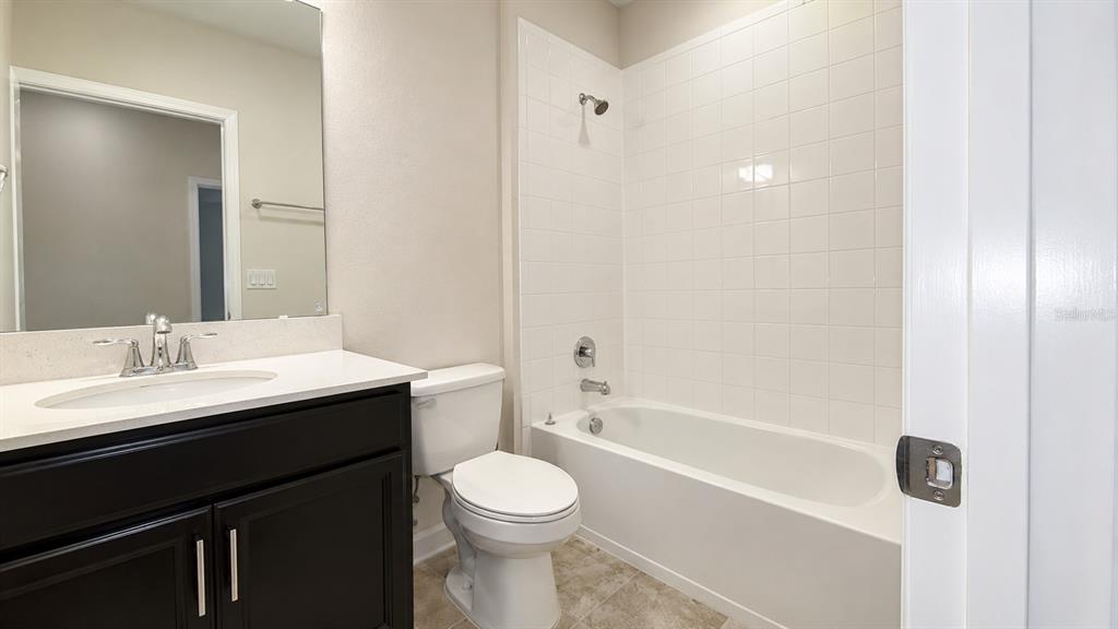 A bathroom features a dark vanity with a white countertop, a toilet, and a tub-shower — 4836 TRIBUTE TRAIL, KISSIMMEE, FL