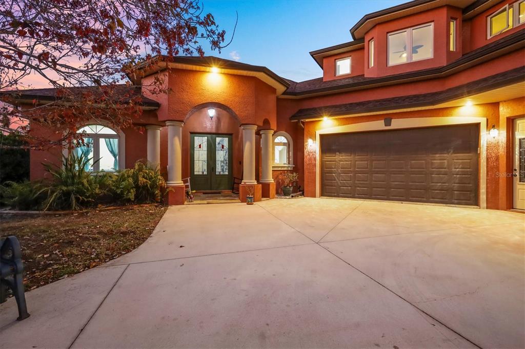 A two-story house with a terracotta exterior, arched entryway, and a three-car garage — 1631 MARIA STREET, ENGLEWOOD, FL
