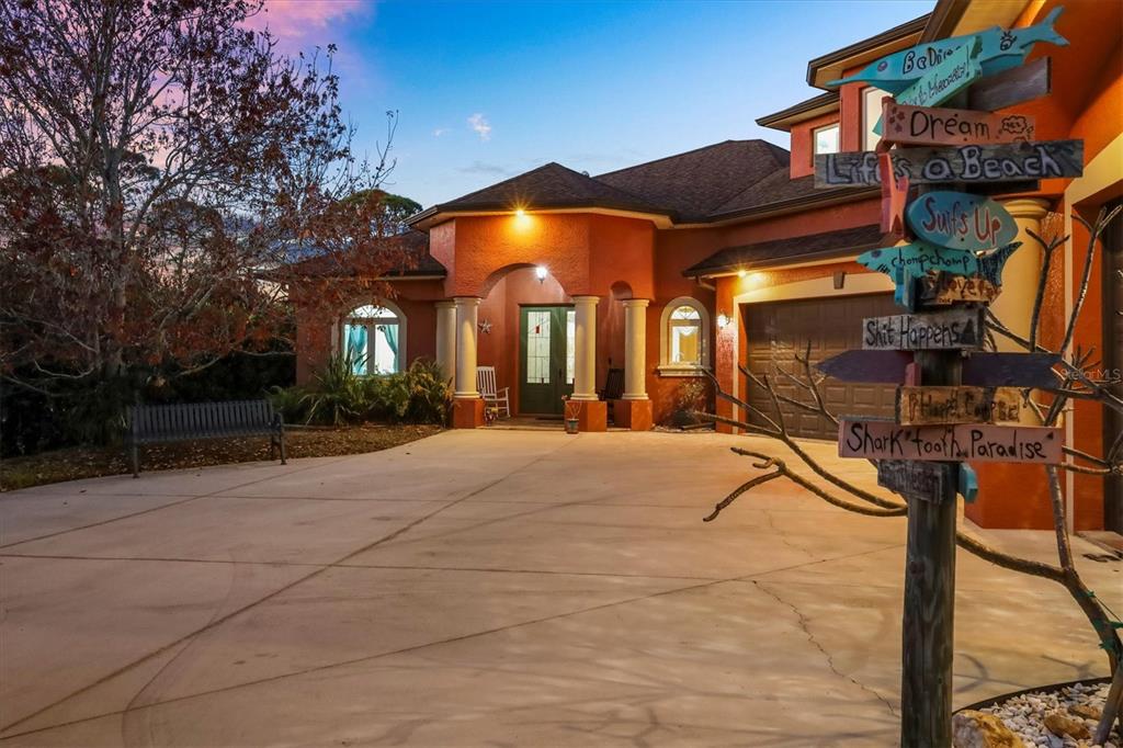 A terracotta-colored house with a concrete driveway and a decorative wooden signpost in the foreground — 1631 MARIA STREET, ENGLEWOOD, FL