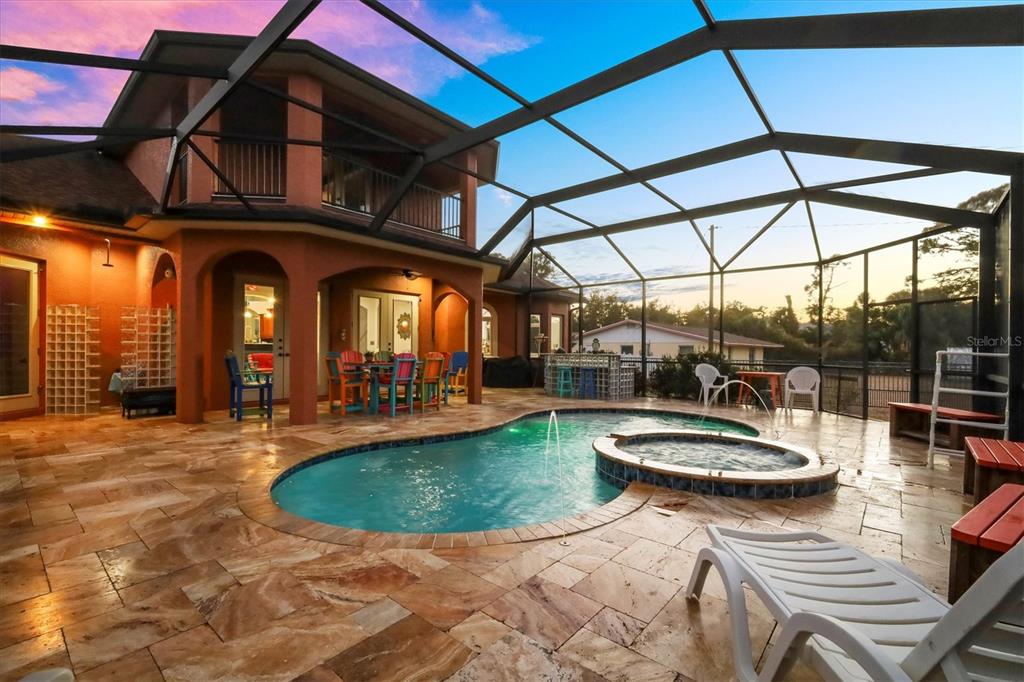 A screened-in patio features a swimming pool, a hot tub, and stone tile flooring — 1631 MARIA STREET, ENGLEWOOD, FL