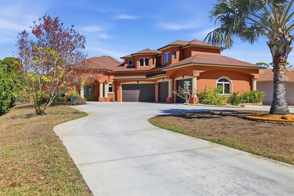 A two-story orange stucco house features a multi-car garage and a concrete driveway — 1631 MARIA STREET, ENGLEWOOD, FL