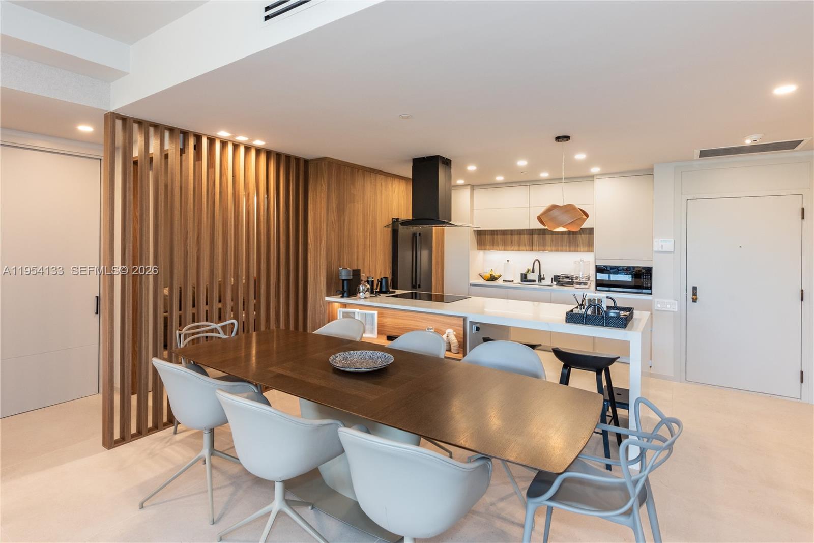 A modern kitchen and dining area feature a wooden slat partition and white cabinetry — 251 Crandon Blvd # 306, Key Biscayne FL 33149, KEY BISCAYNE, FL