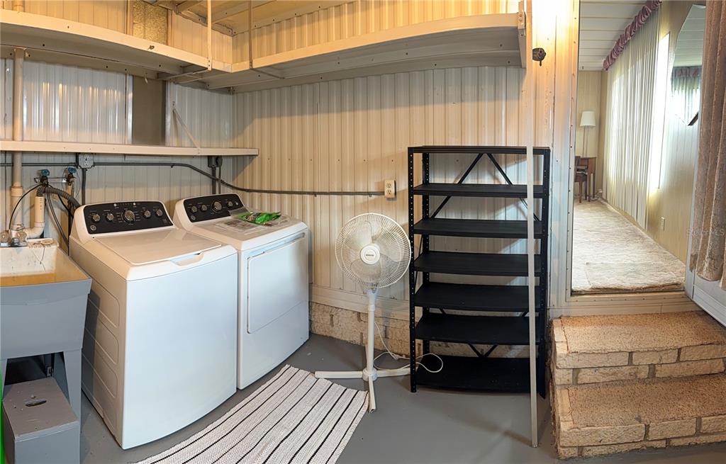 A laundry room features a washer, dryer, utility sink, shelving, and a black metal rack — 3301 ALT 19 UNIT 167, DUNEDIN, FL