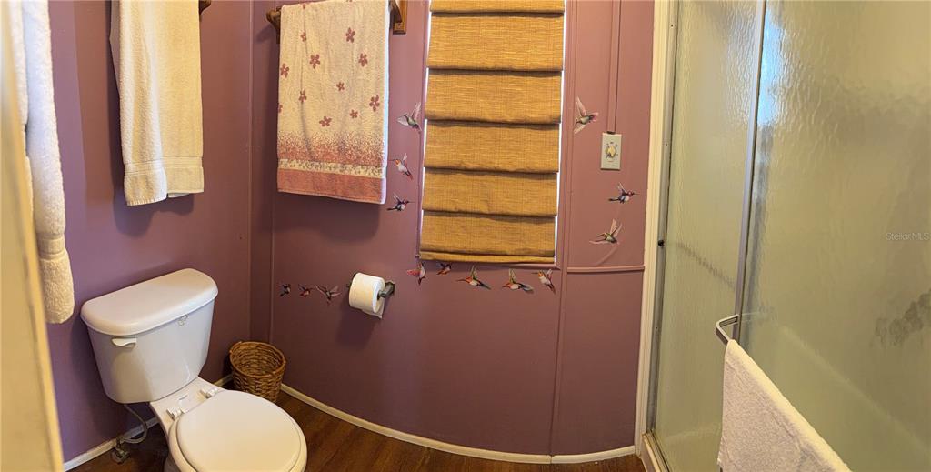 A bathroom with purple walls, a toilet, a shower stall, and hummingbird wall decals — 3301 ALT 19 UNIT 167, DUNEDIN, FL