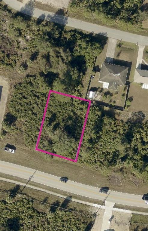 An aerial view shows a rectangular, wooded vacant lot outlined in pink along a road — PRICE BOULEVARD, NORTH PORT, FL