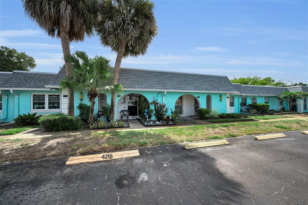 A turquoise single-story apartment building features arched entryways and a parking lot in front — 4218 TERRAPIN PLACE UNIT D, NEW PORT RICHEY, FL