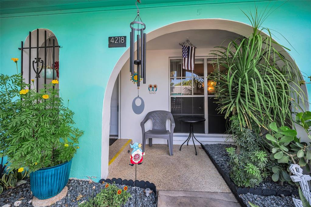 A teal-colored house exterior features an arched entryway, a small patio, and potted plants — 4218 TERRAPIN PLACE UNIT D, NEW PORT RICHEY, FL