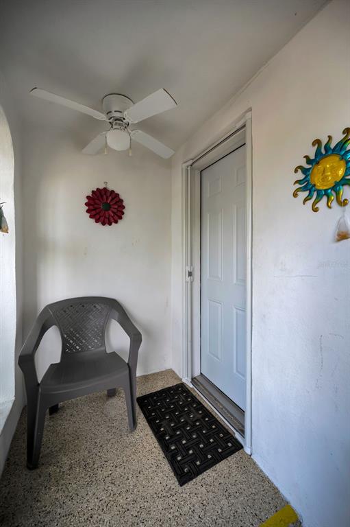 A small covered porch features a gray plastic chair, a ceiling fan, and a door — 4218 TERRAPIN PLACE UNIT D, NEW PORT RICHEY, FL