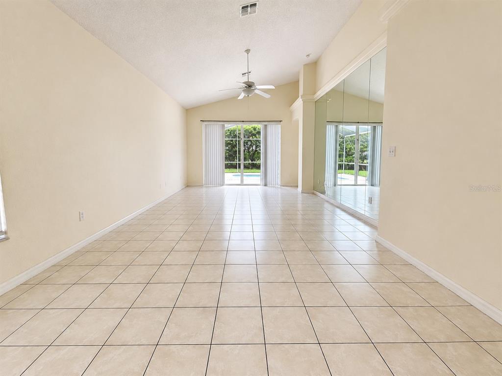 An empty room with beige carpet, light-colored walls, two windows, and an arched window above — 16647 FRESH MEADOW DRIVE, CLERMONT, FL