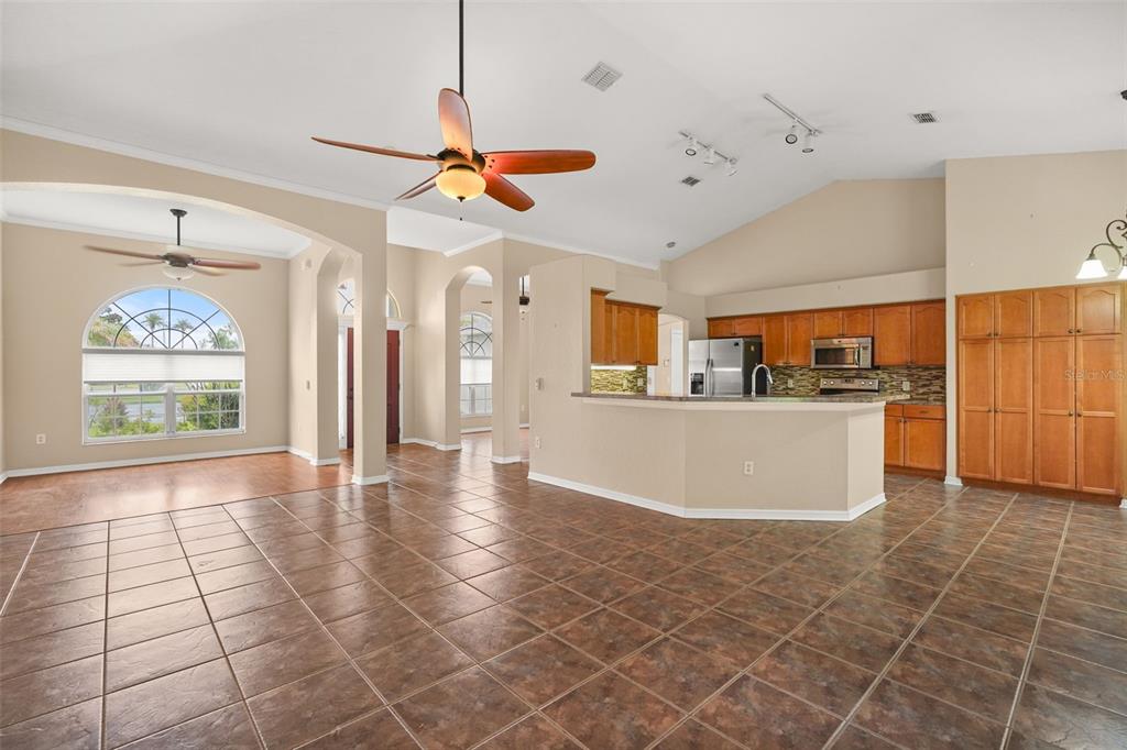 An open-concept living area features tile flooring, a kitchen with wood cabinets, and vaulted ceilings — 3806 OPAL CIRCLE, ST CLOUD, FL