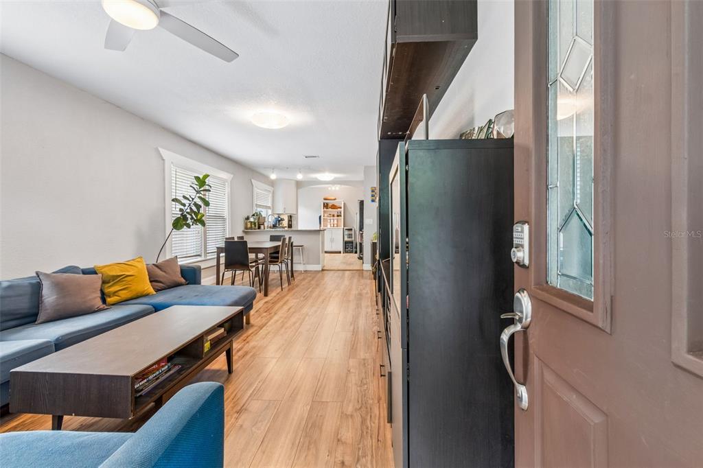 A view from an open doorway into a living room with wood-look flooring and furniture — 1220 E EMMA STREET, TAMPA, FL
