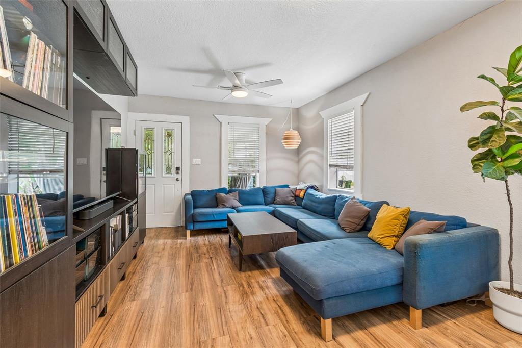 A living room features a blue sectional sofa, wood flooring, and a large media console — 1220 E EMMA STREET, TAMPA, FL