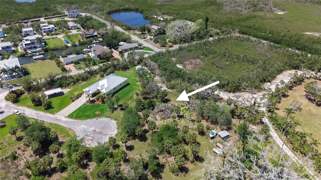 An aerial view shows a residential property with a house, surrounding trees, and a dirt path — 1910 KENNEDY COURT, TERRA CEIA, FL