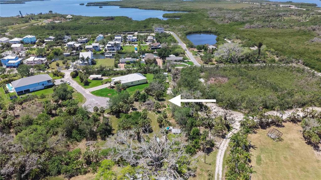 An aerial view shows a residential neighborhood with houses, lush vegetation, and a small lake — 1910 KENNEDY COURT, TERRA CEIA, FL