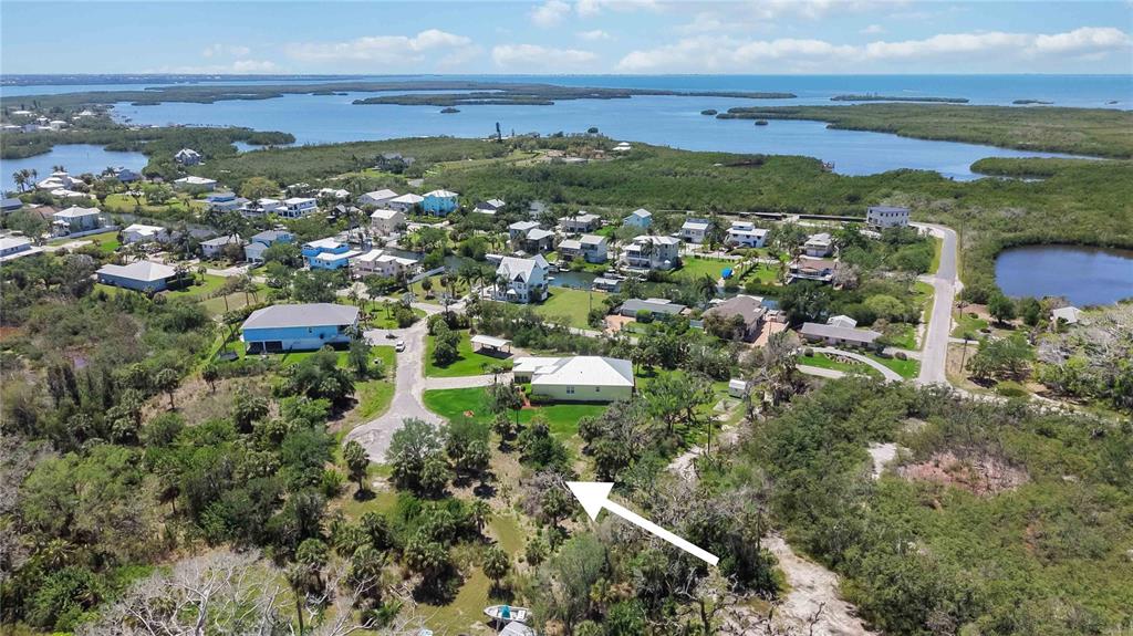 An aerial view shows a residential neighborhood with a white-roofed house and surrounding vegetation — 1910 KENNEDY COURT, TERRA CEIA, FL