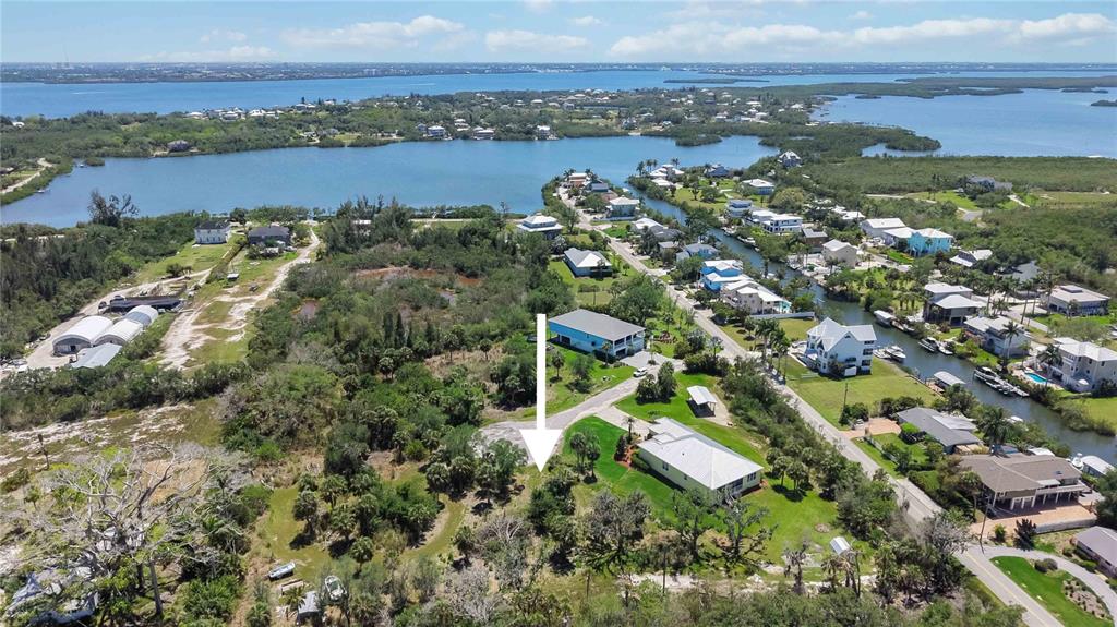 An aerial view shows a vacant, wooded lot marked by a white arrow near water — 1910 KENNEDY COURT, TERRA CEIA, FL