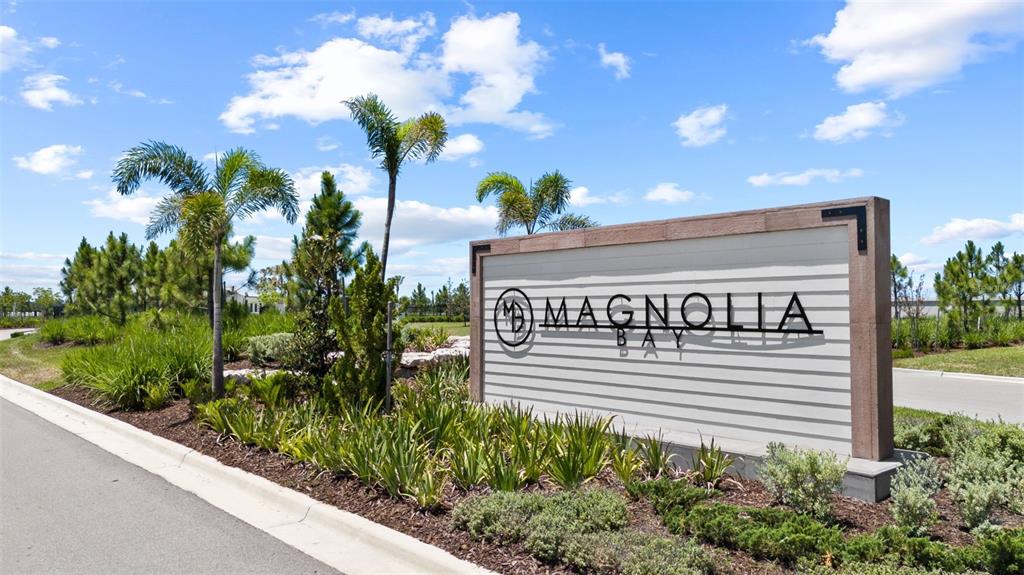 A sign for Magnolia Bay stands in a landscaped area with palm trees and sky — 293 HOLLY BANK AVENUE, NOKOMIS, FL