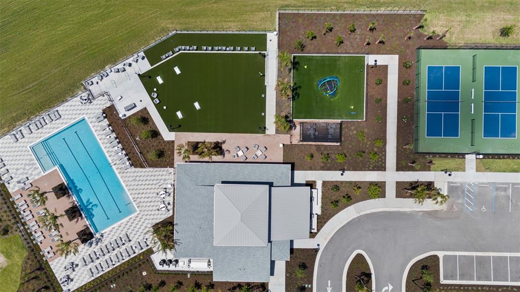 An aerial view shows a community center with a swimming pool, playground, and tennis courts — 293 HOLLY BANK AVENUE, NOKOMIS, FL