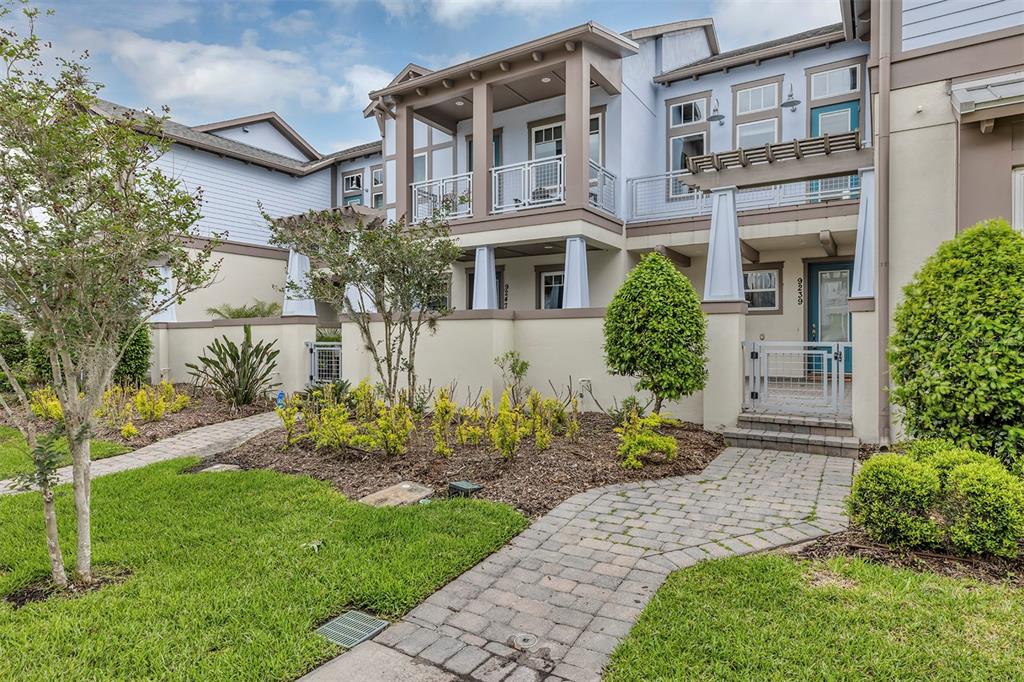 The exterior of a multi-story townhouse features a paved walkway, small front yard, and balconies — 9239 DOHERTY PLACE, ORLANDO, FL