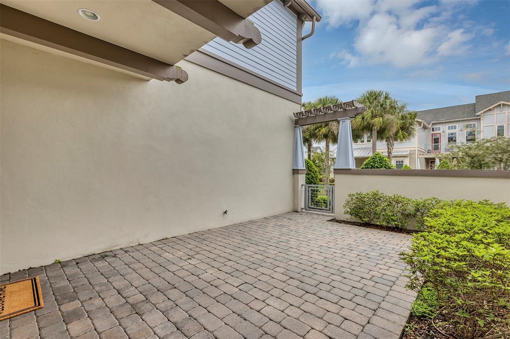 A paved patio area features a stucco wall, a small gate, and a wooden pergola — 9239 DOHERTY PLACE, ORLANDO, FL