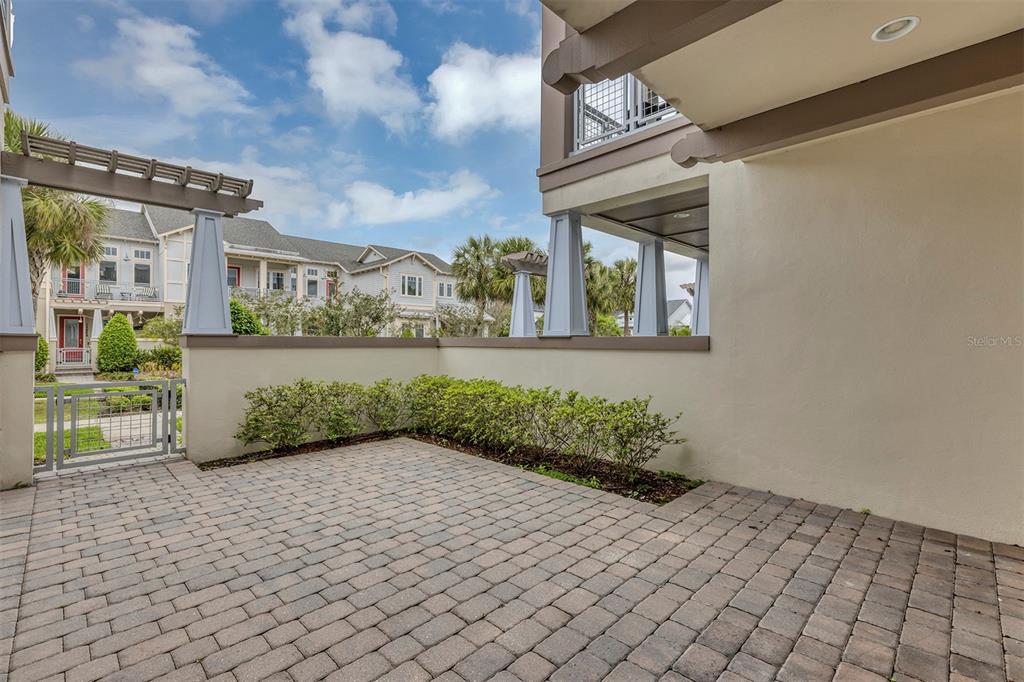 A paved patio area is enclosed by a low wall and a metal gate — 9239 DOHERTY PLACE, ORLANDO, FL