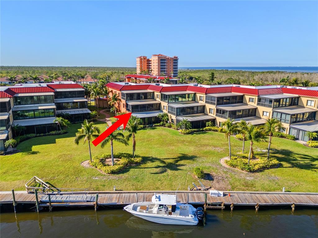 An aerial view shows a multi-story waterfront condominium building with a boat docked nearby — 3230 SOUTHSHORE DRIVE UNIT 36B, PUNTA GORDA, FL