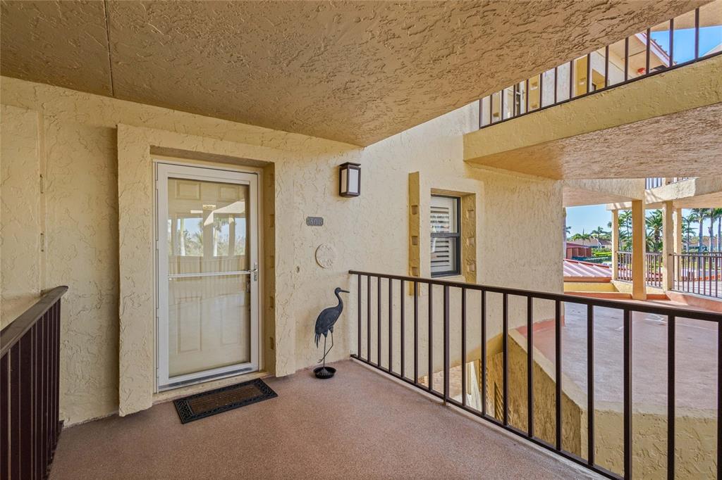 An outdoor balcony features a white door, a metal railing, and a decorative bird statue — 3230 SOUTHSHORE DRIVE UNIT 36B, PUNTA GORDA, FL