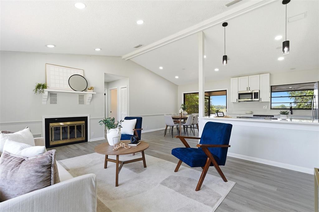 An open-concept living and dining area features a fireplace, blue accent chairs, and white cabinetry — 1020 S SCENIC HIGHWAY, LAKE WALES, FL