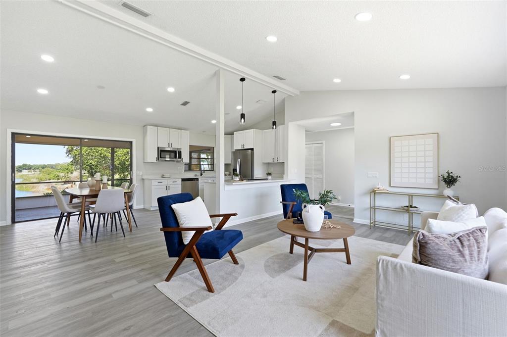 A bright, open-concept living and dining area features white cabinetry, gray flooring, and lake views — 1020 S SCENIC HIGHWAY, LAKE WALES, FL