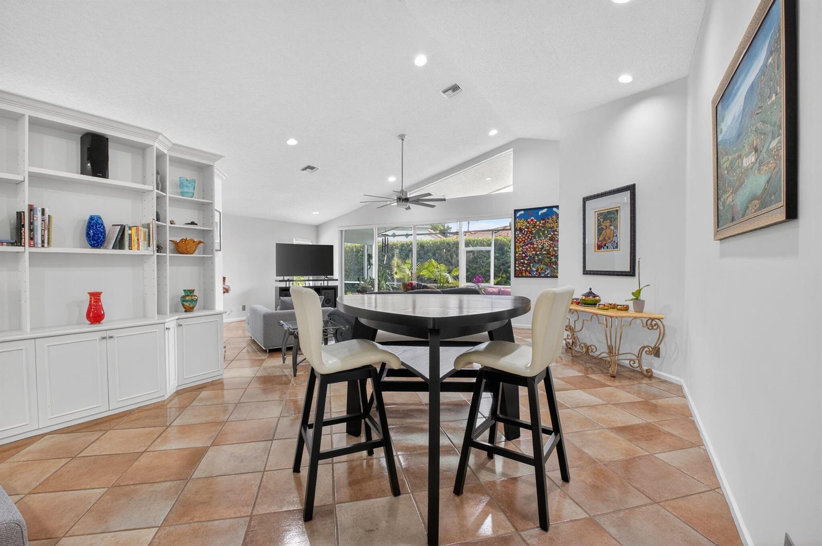 A dining area with a round table and chairs sits in an open-concept living space — 11590 Creekside Drive, Boynton Beach FL 33437, BOYNTON BEACH, FL