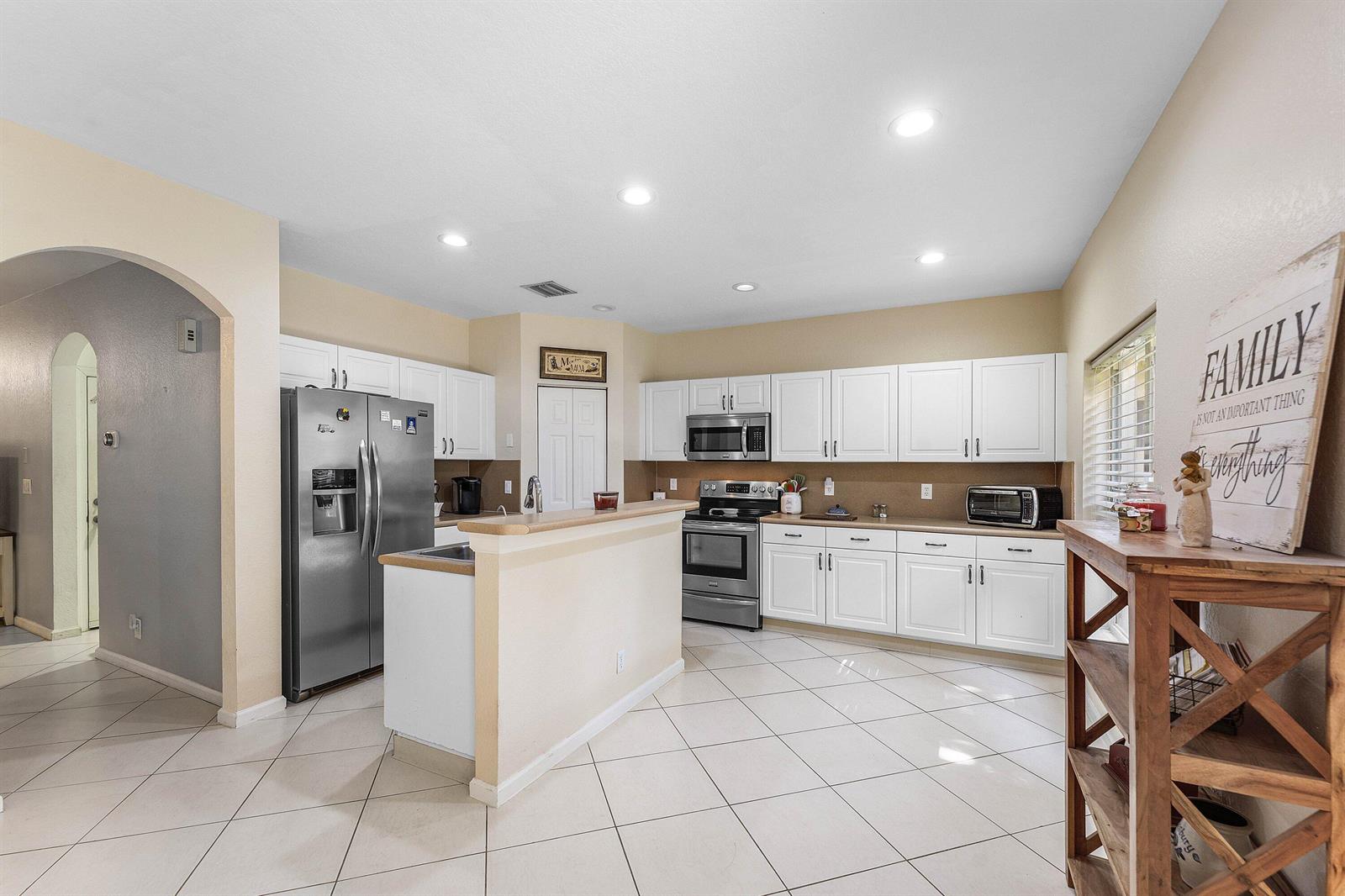 A kitchen with white cabinets, stainless steel appliances, and beige tile flooring — 331 Spruce Street, Boynton Beach FL 33426, BOYNTON BEACH, FL