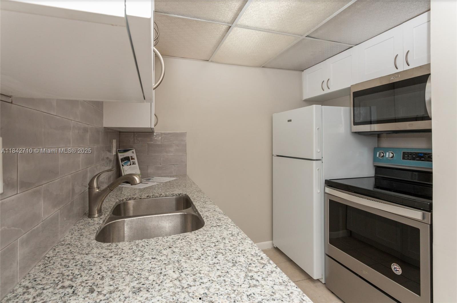 A kitchen features a double sink, granite countertops, white cabinets, and stainless steel appliances — 2145 Pierce St # 218, Hollywood FL 33020, HOLLYWOOD, FL
