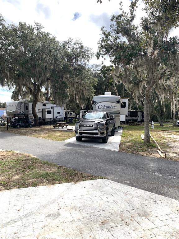 A black pickup truck is parked in front of a Columbus fifth-wheel trailer at a campsite — 15991 NE 243RD PLACE ROAD UNIT 54, FORT MC COY, FL