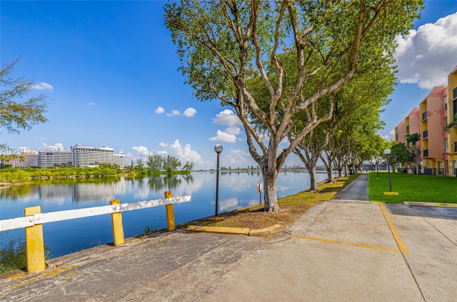 A paved walkway runs alongside a lake lined with trees and a residential building — 4805 NW 7th St # 15, Miami FL 33126, MIAMI, FL