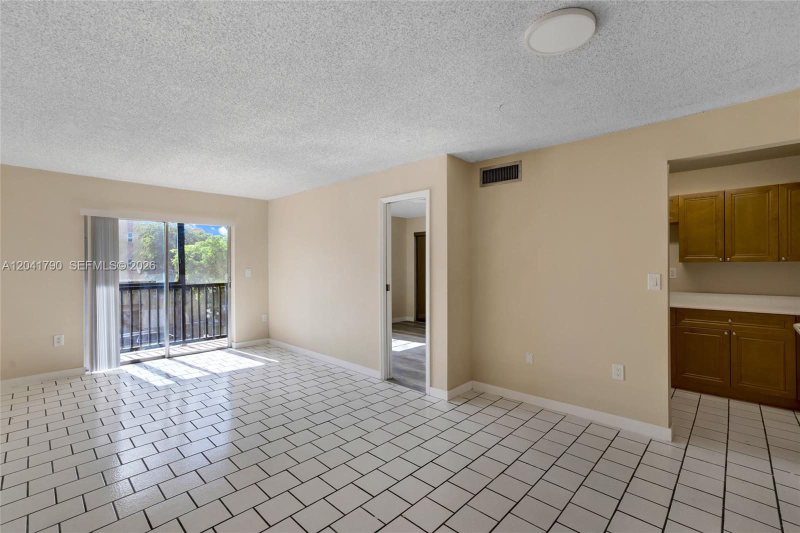 A living room with white tiled floors, beige walls, and an adjacent kitchen area — 4805 NW 7th St # 15, Miami FL 33126, MIAMI, FL