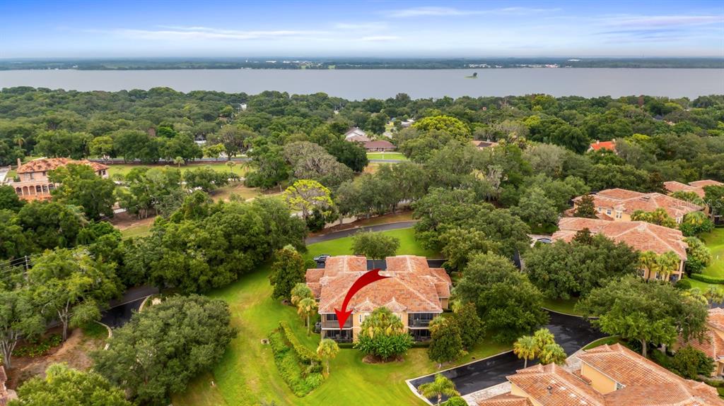 An aerial view shows a multi-story residential building with a red arrow pointing toward it — 82 CAMINO REAL BOULEVARD UNIT 82, HOWEY IN THE HILLS, FL