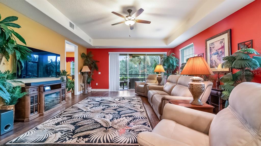 A living room features a patterned rug, leather furniture, red and yellow walls, and sliding doors — 82 CAMINO REAL BOULEVARD UNIT 82, HOWEY IN THE HILLS, FL