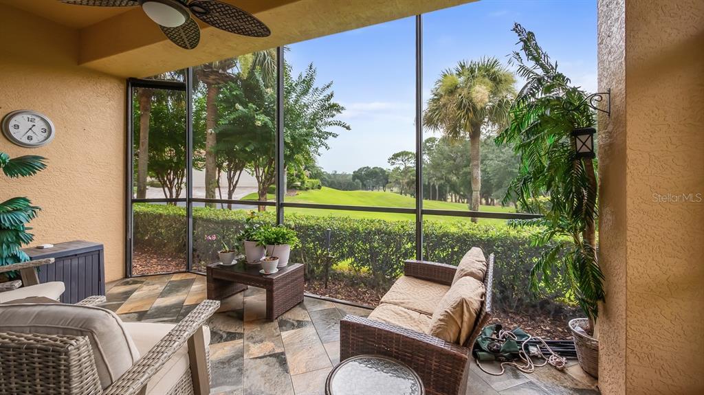 A screened-in patio with tile flooring, wicker furniture, and a view of green landscaping — 82 CAMINO REAL BOULEVARD UNIT 82, HOWEY IN THE HILLS, FL