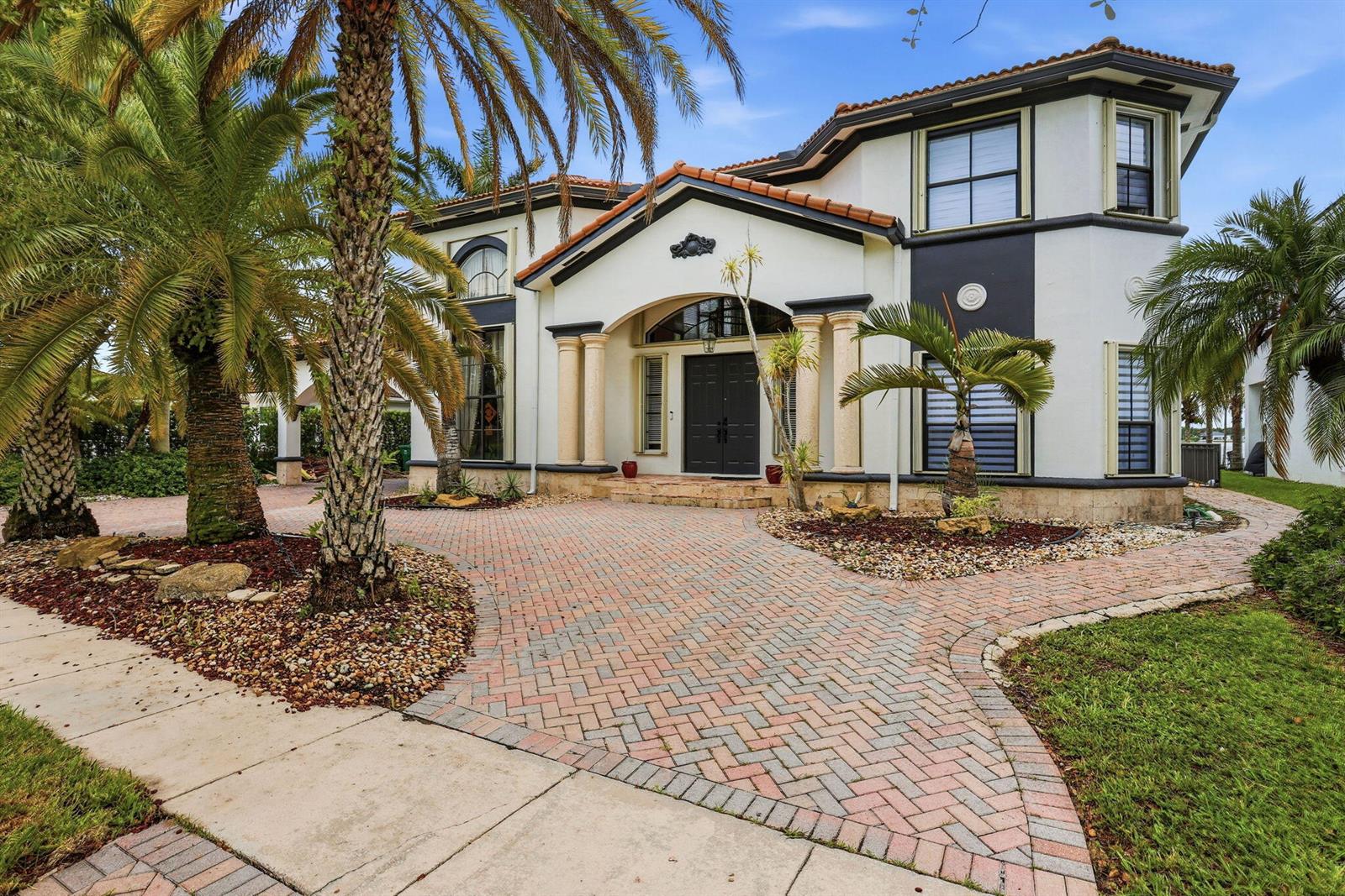 A two-story house with a brick paver driveway, palm trees, and a covered front entrance — 18662 SW 17th Court, Miramar FL 33029, MIRAMAR, FL