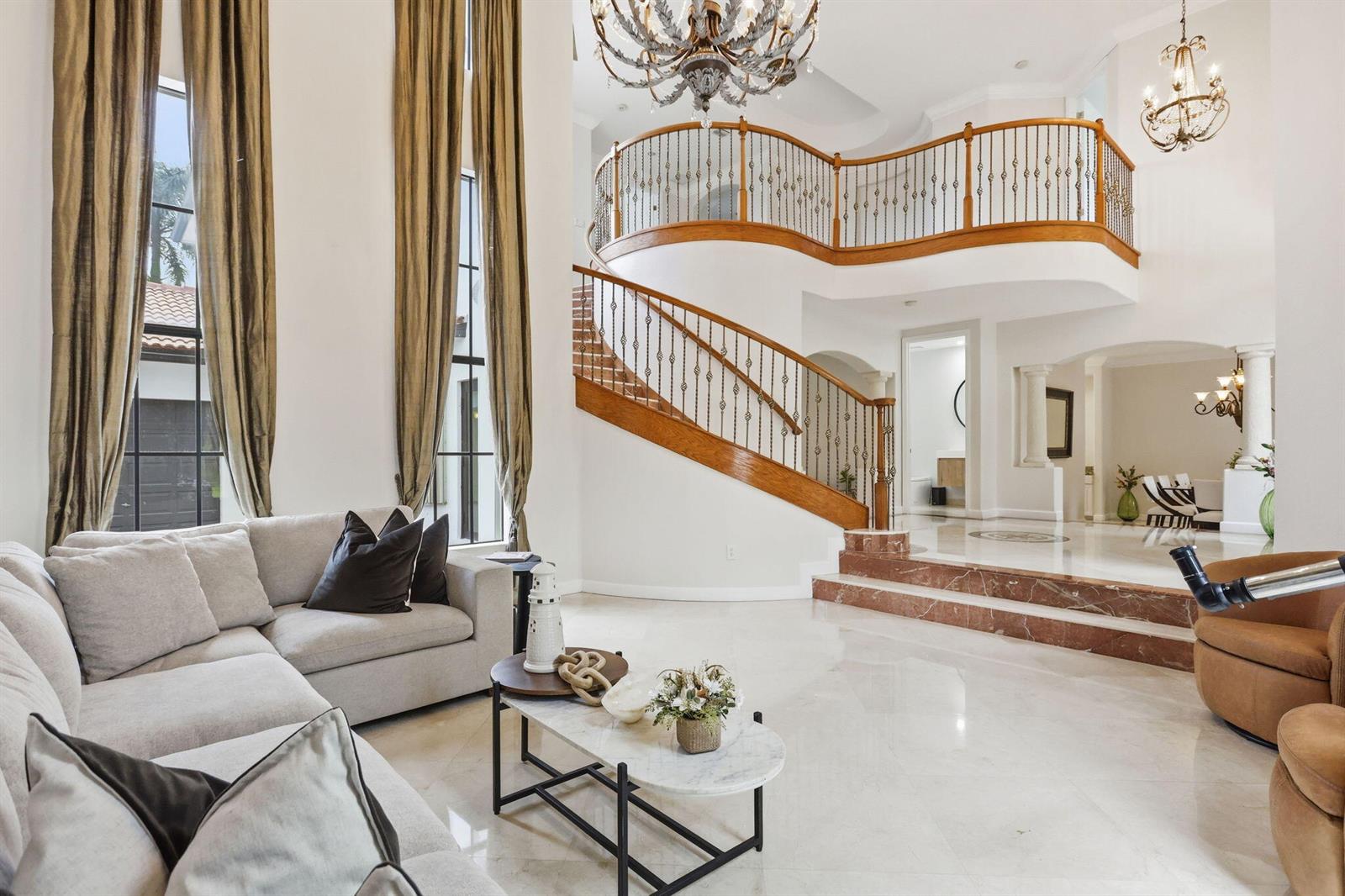 A grand foyer features a curved wooden staircase, marble floors, and a large chandelier — 18662 SW 17th Court, Miramar FL 33029, MIRAMAR, FL