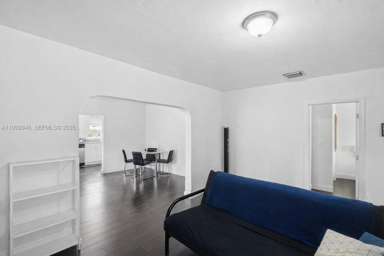 A living room with dark wood floors leads to a dining area through an archway — 3645 SW 25th Ter, Miami FL 33133, MIAMI, FL