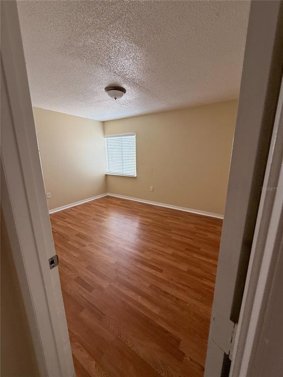 An empty bedroom features light-colored walls, a single window with blinds, and wood-look flooring — 800 N FISKE BOULEVARD UNIT 410, COCOA, FL