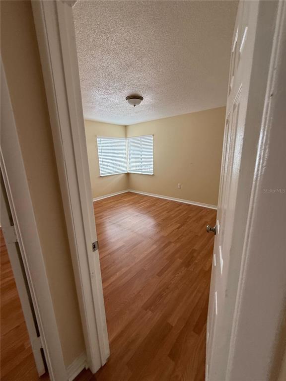 An empty bedroom features light wood-look flooring, beige walls, and a corner window with blinds — 800 N FISKE BOULEVARD UNIT 410, COCOA, FL