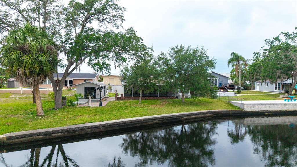 A canal-front property features a small shed, a screened-in porch, and mature trees — 5822 RIVER ROAD, NEW PORT RICHEY, FL