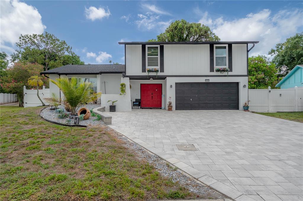 A two-story house features a red front door, a black garage door, and a paved driveway — 7312 NOVA CIRCLE, TAMPA, FL