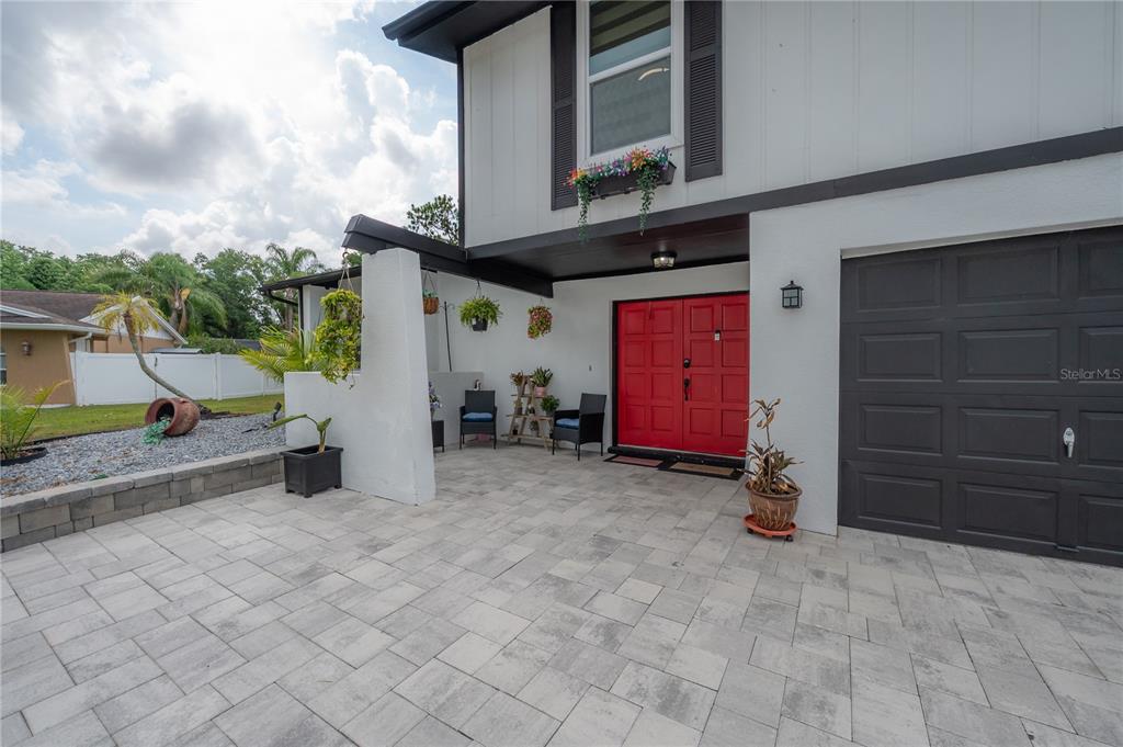 A paved driveway leads to a house with a red double door and garage — 7312 NOVA CIRCLE, TAMPA, FL