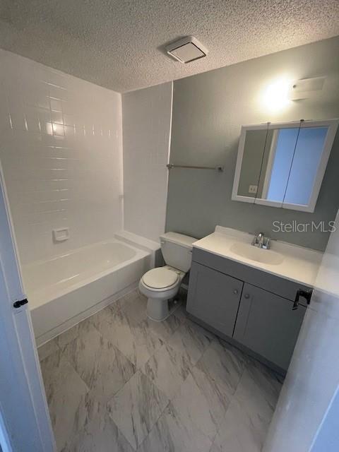 A bathroom features a gray vanity, a white toilet, and a shower-tub combination with white tiles — 124 LOBLOLLY COURT UNIT D, OLDSMAR, FL