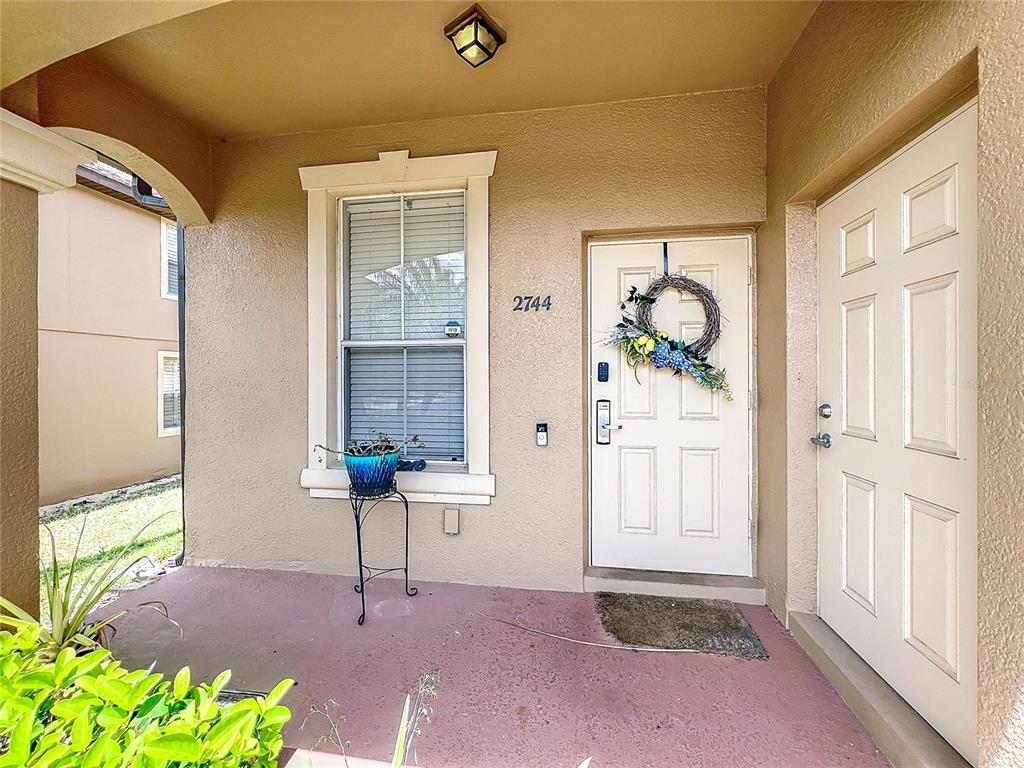 A covered front porch features a white door, a window, and a potted plant — 2744 CALABRIA AVENUE, DAVENPORT, FL