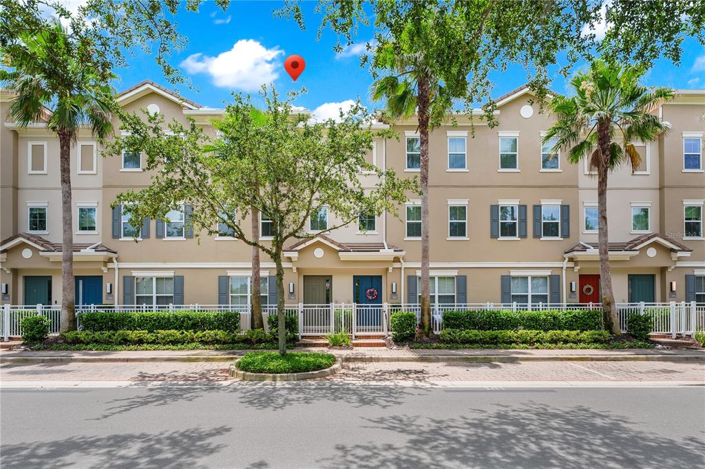 A row of three-story townhomes with tan stucco facades and palm trees in front — 763 GREYBULL RUN, LAKE MARY, FL